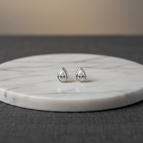 Teardrop-shaped earrings on a marble stand with a neutral background
