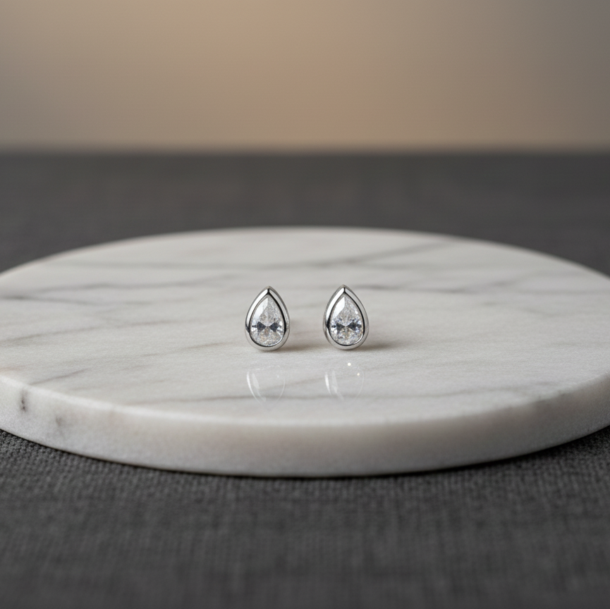 Teardrop-shaped earrings on a marble stand with a neutral background